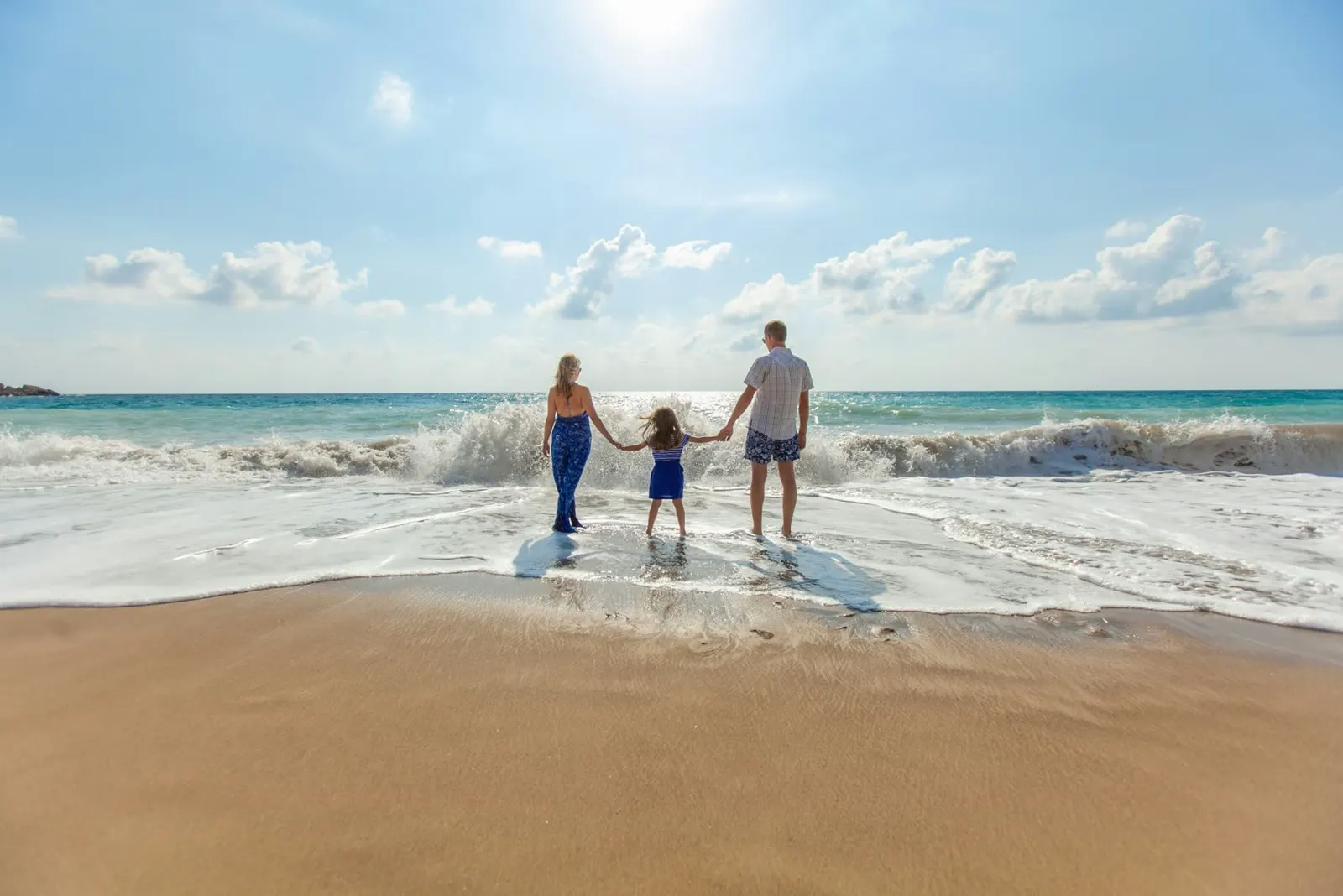 A family walking a wide beach at low tide